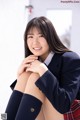 A young woman in a school uniform sitting on the floor.